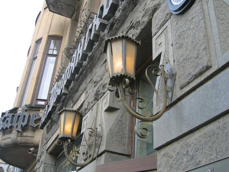 Светильники у фасада здания на Спб Flashlamps: камень, кованый металл и вывеска «Кафе»
