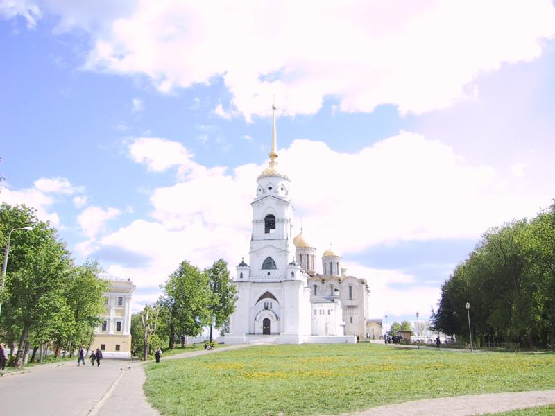 Белокаменная церковь с золотым куполом и шпилем на фоне голубого неба