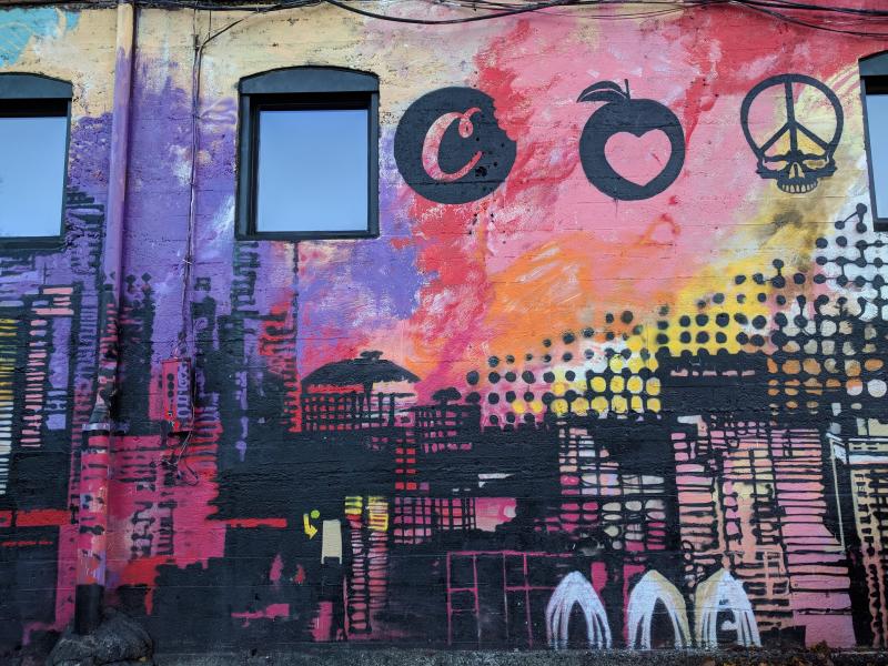 Стена с граффити в Сиэтле: яблоко с сердцем, череп с пиктограммой мира и бетонный силуэт города