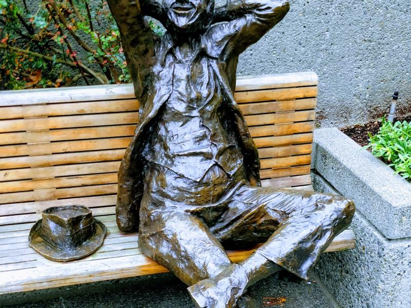 Бронзовая фигура на скамейке в Сиэтле: улыбающийся мужчина с шляпой рядом